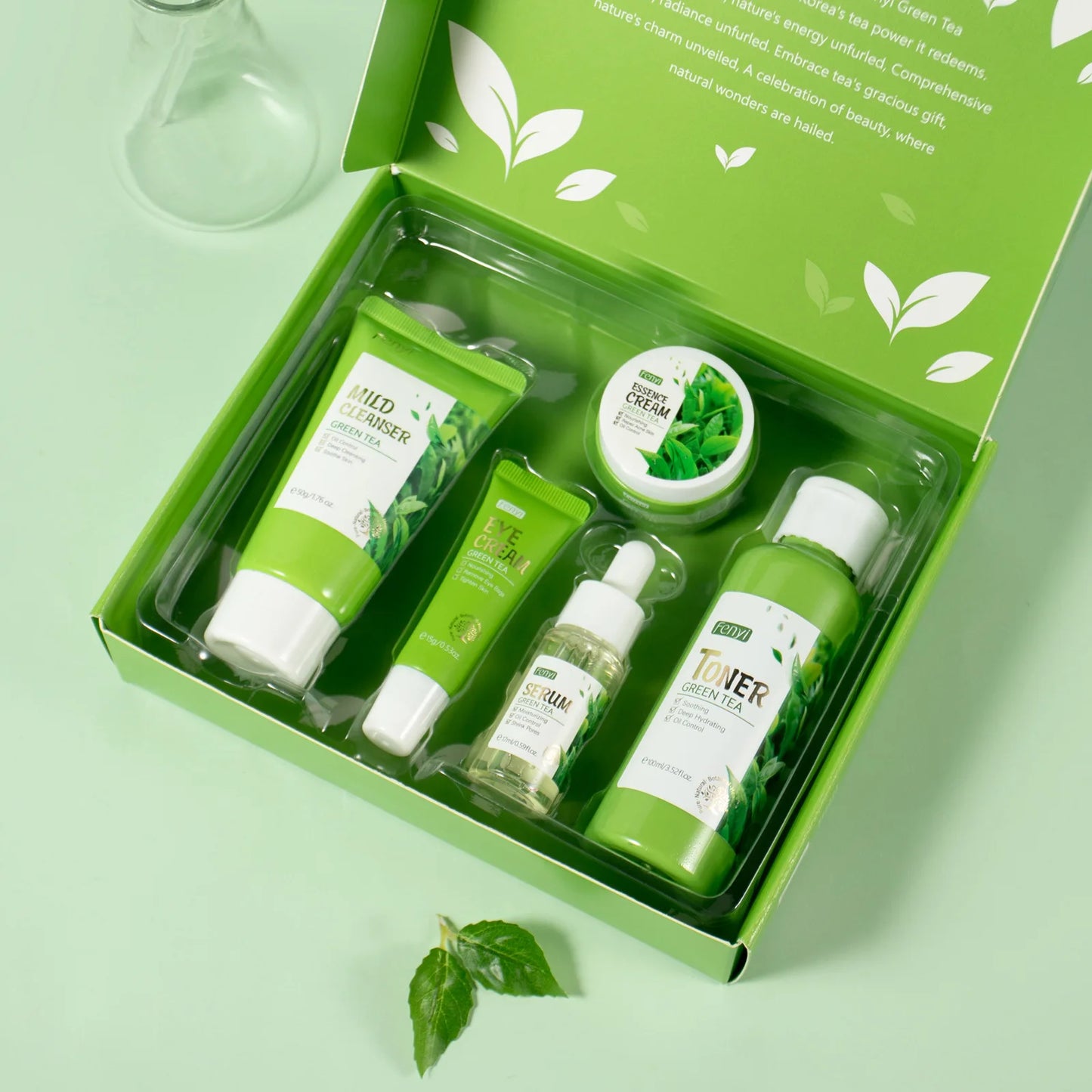 Set of green skincare products in a box on a light green background